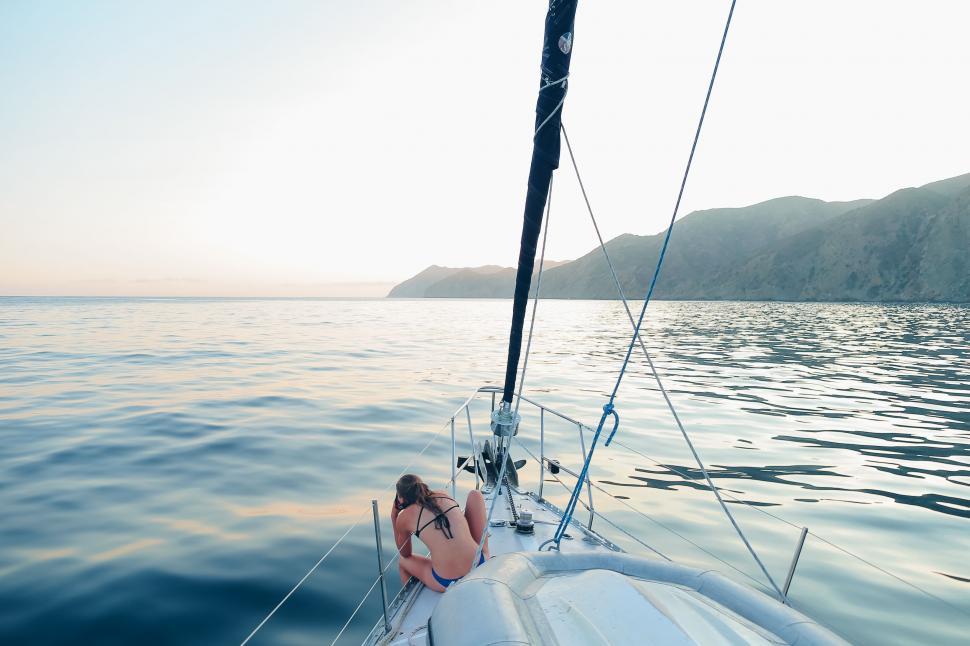 Free Image of Woman Sitting on Bow of Sailboat 