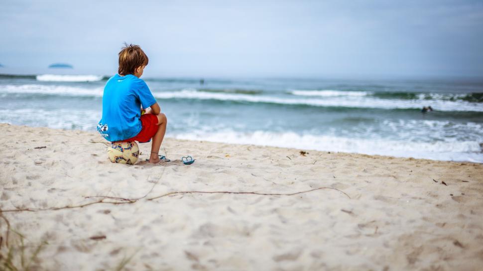 Free Image of Young Boy Sitting on Top of Sandy Beach 