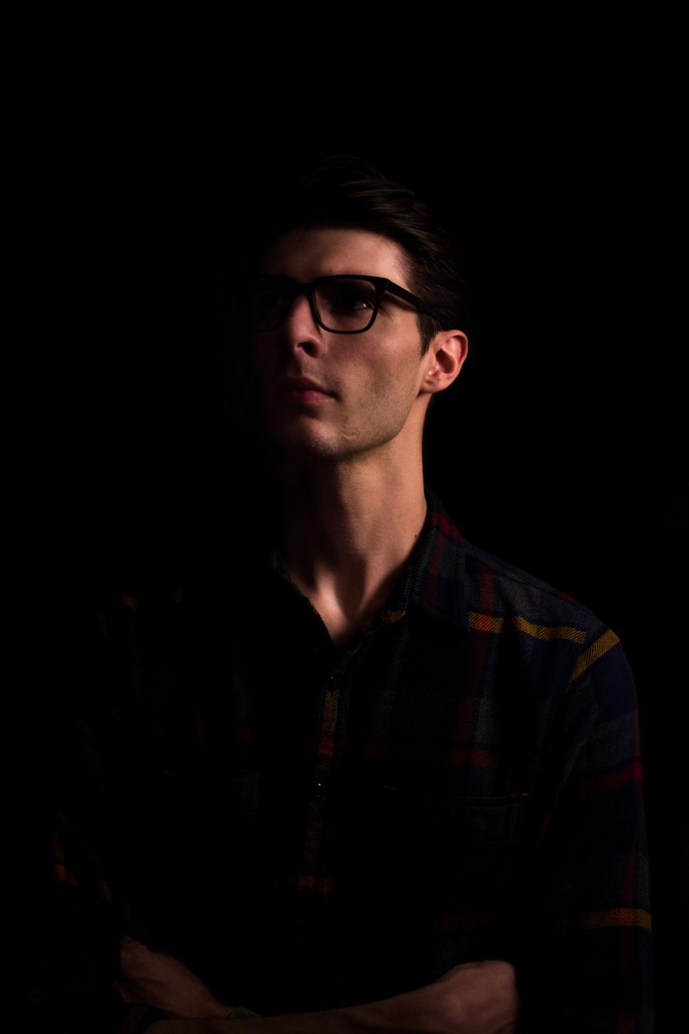 Free Image of Man With Glasses Standing in the Dark 