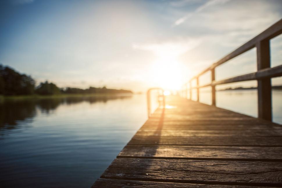 Free Image of Sun Setting Over Water on Dock 