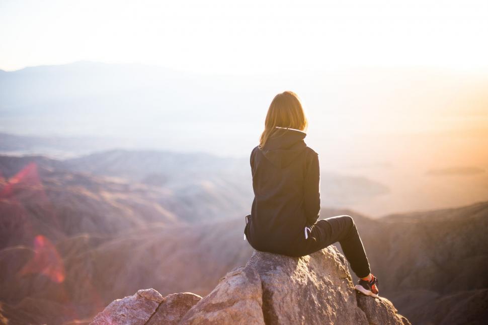 Free Image of Woman Sitting on Top of a Large Rock 