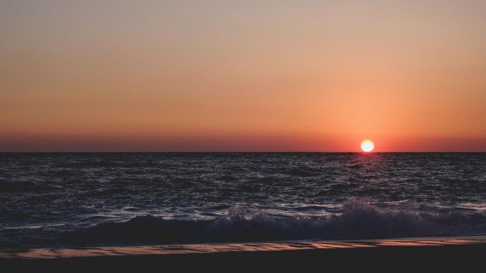 Free Image of Sun Setting Over Ocean With Waves 