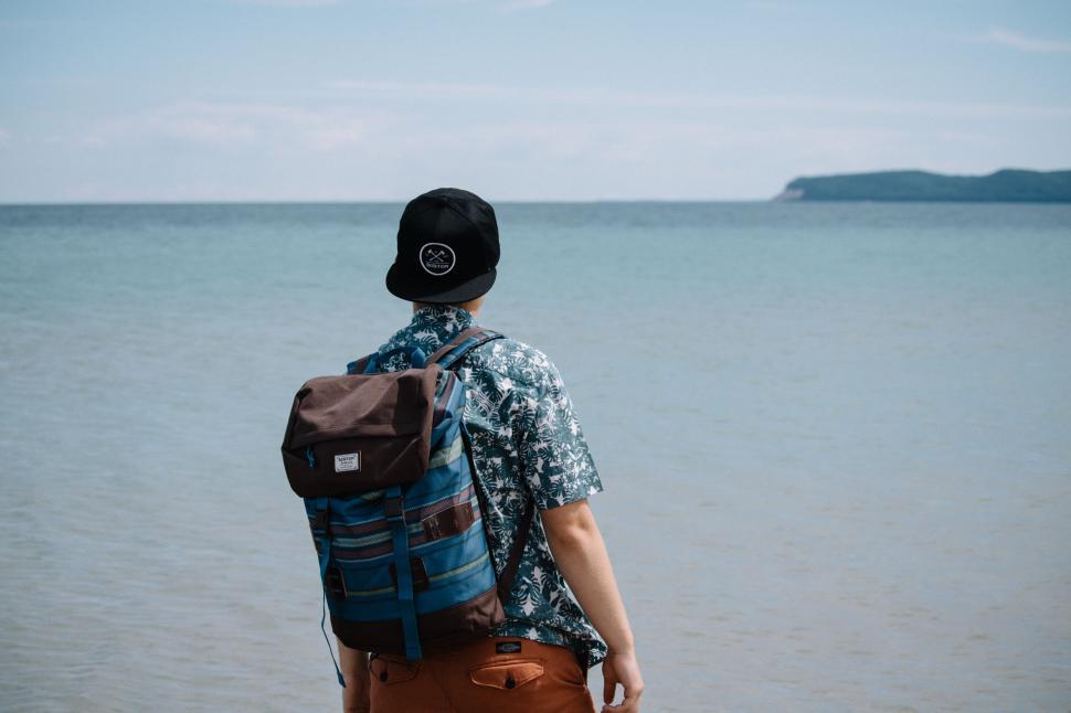 Free Image of Man With Backpack Looking Out at the Ocean 