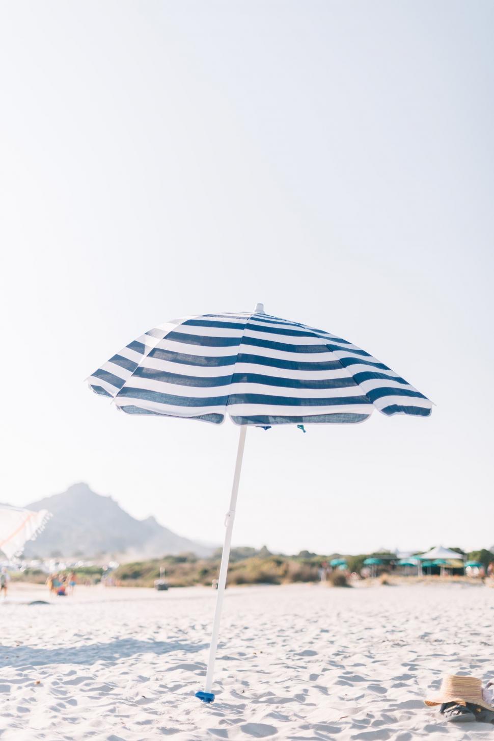 Free Image of Blue and White Umbrella on Sandy Beach 