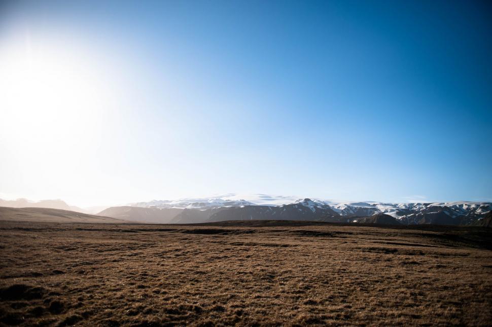 Free Image of Sun Shining Over Field With Mountains in Background 
