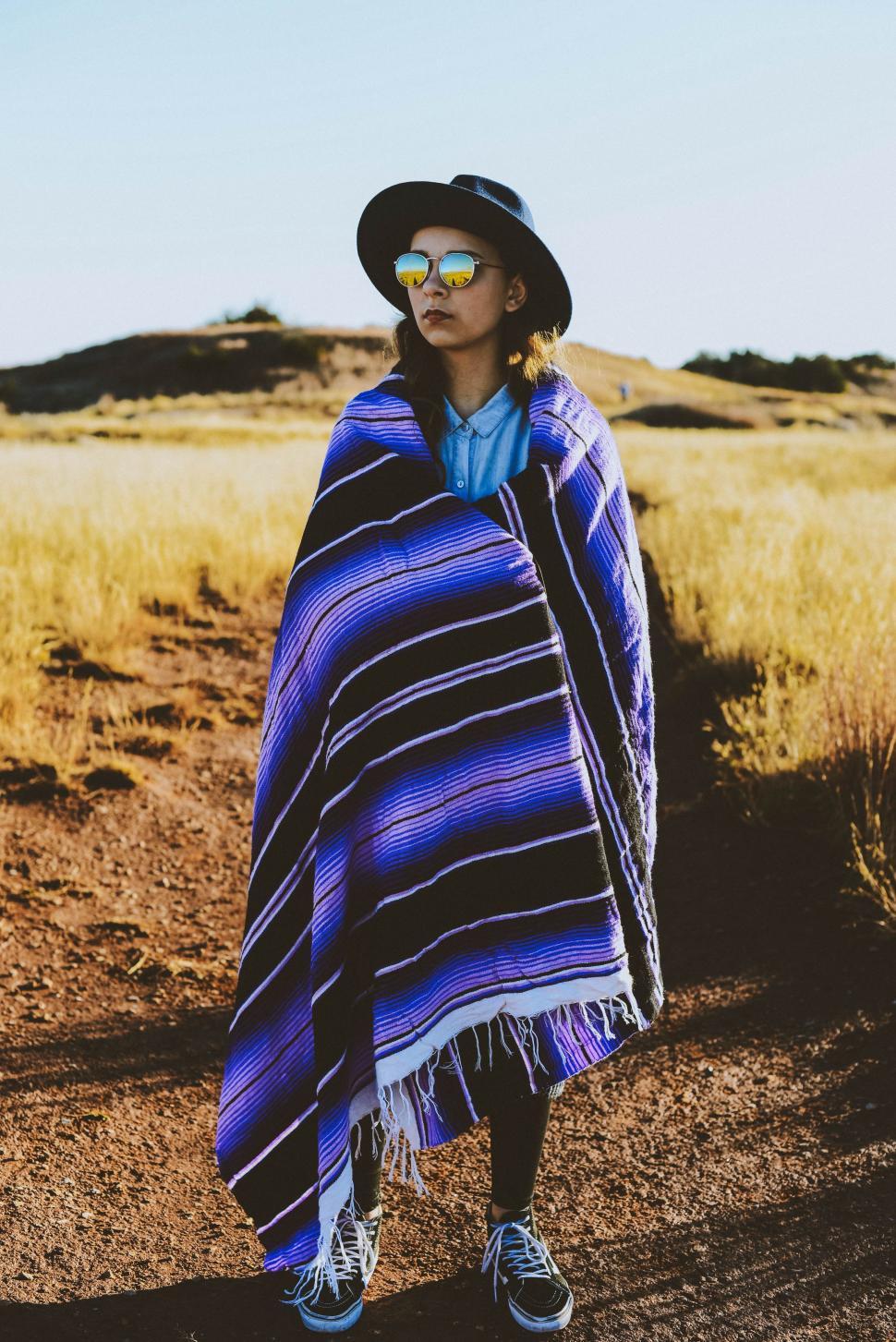 Free Image of Woman Standing in Field Wearing Blue and Black Blanket 
