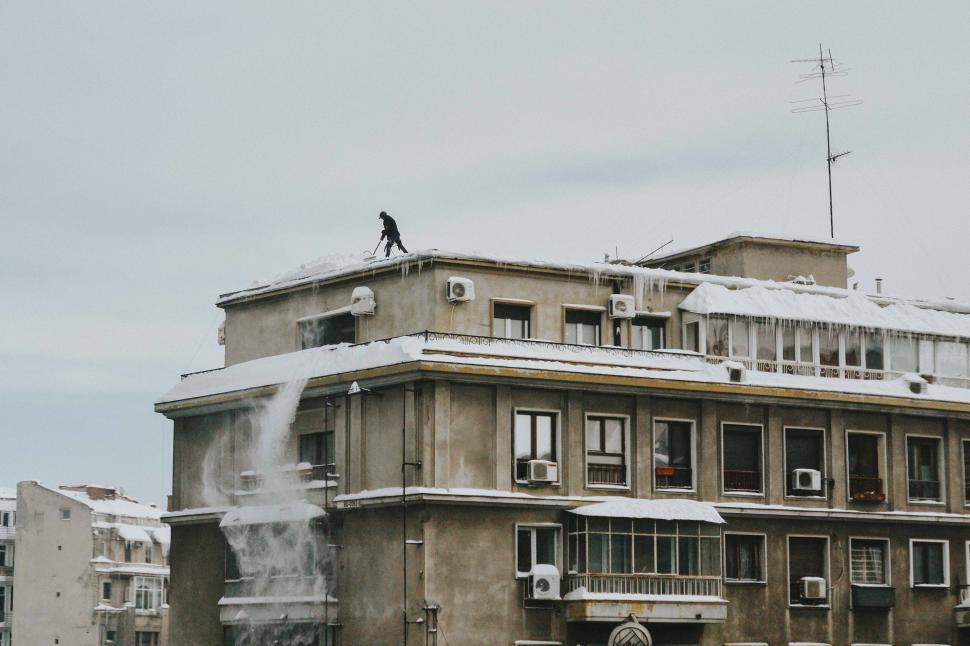 Free Image of Man Stands on Top of Snow-Covered Building 