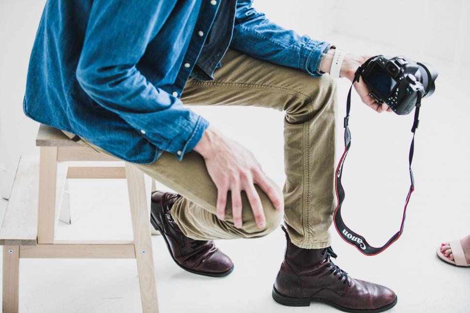 Free Image of Man Sitting on Stool With Camera 