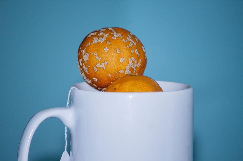 Free Image of Two Oranges in a White Cup on a Blue Background 
