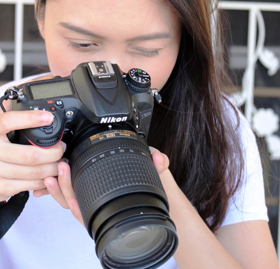 Free Image of Asian girl takes photo with Nikon camera  