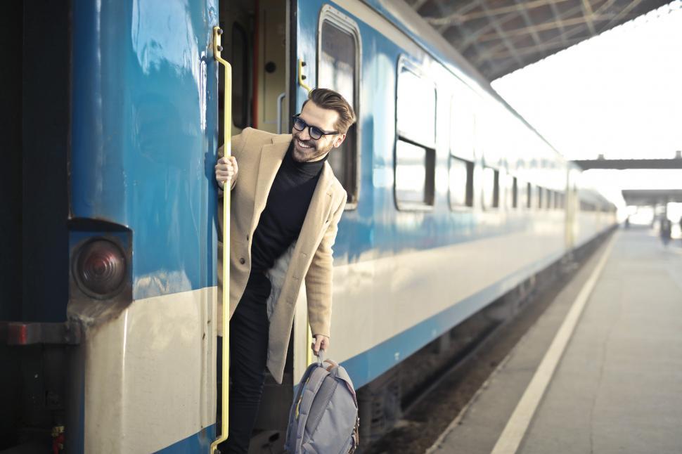 Download Free Stock Photo of Young Adult Man looks out of the open train door during a stop 