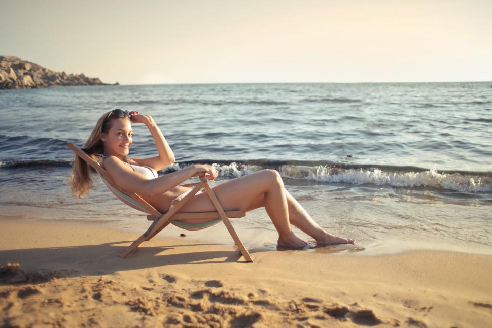 Free Image of Young Woman relaxing on deckchair near seashore at beach 