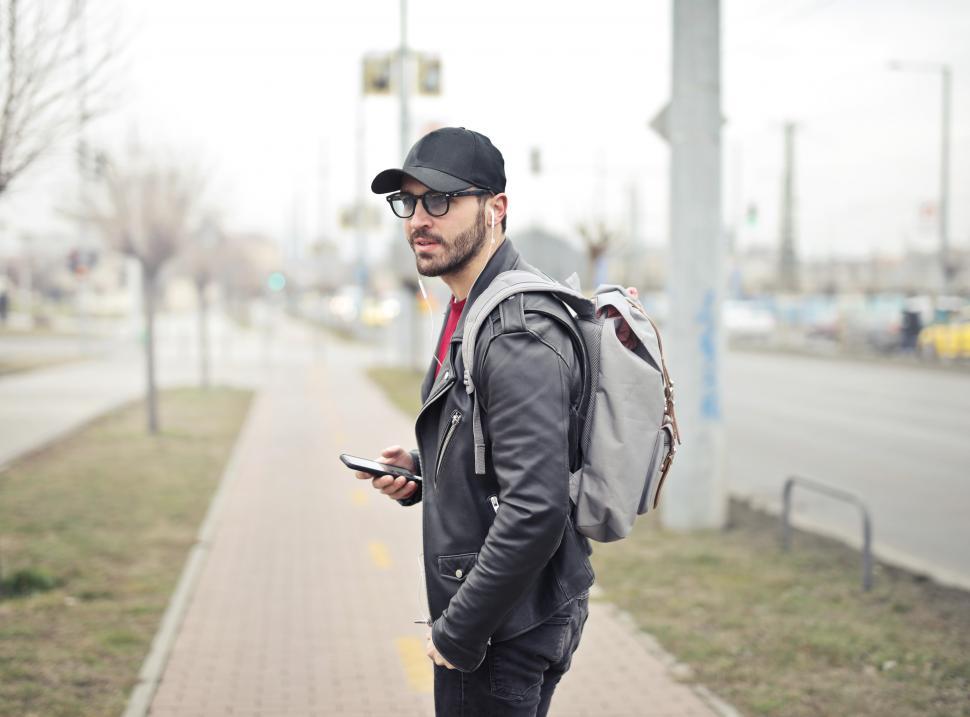 Download Free Stock Photo of Young Adult man wearing black leather jacket holding smartphone 