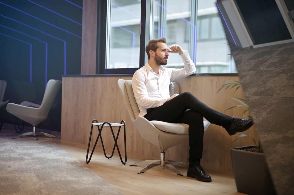 Free Image of Young Adult man sitting on office chair, thinking and consideri 