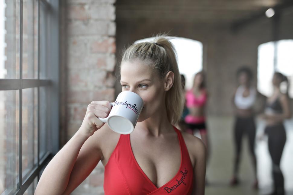 Free Image of Young Woman Wearing Red Tank Top drinking a cup of coffee 