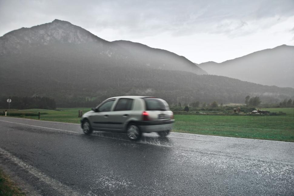 Free Image of Car on the road in the rain with mountain 