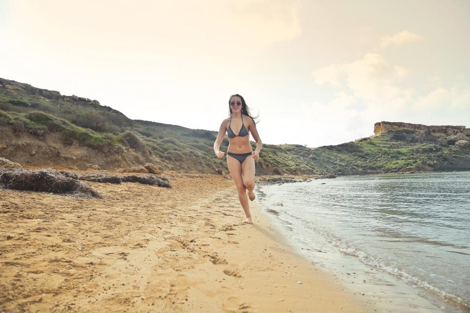 Free Image of Woman Wearing Grey Bikini Running On White Sand at Seashore 