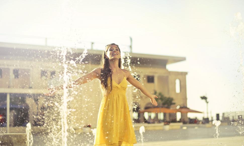 Free Image of Beautiful young woman dancing under the fountain on the street 