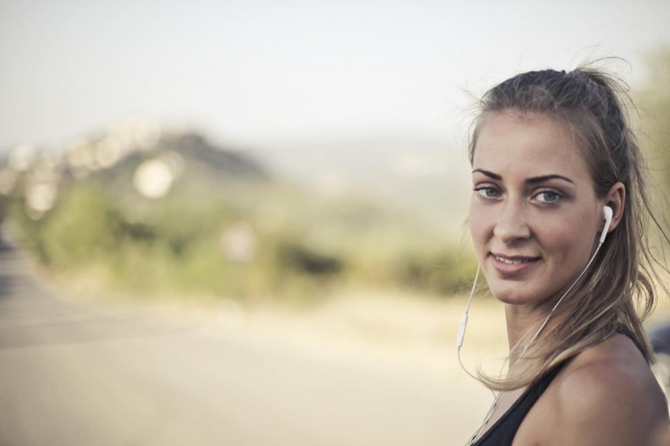 Free Image of Woman In Black Tank Top And White Earbuds 