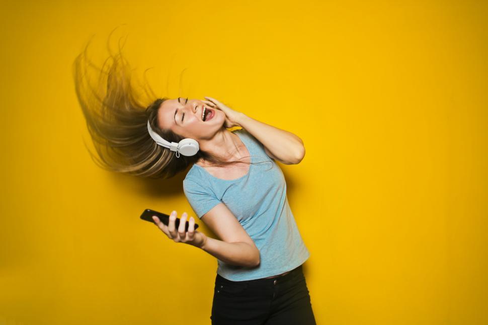 Free Image of Excited woman dancing and listening music with headphones and sm 
