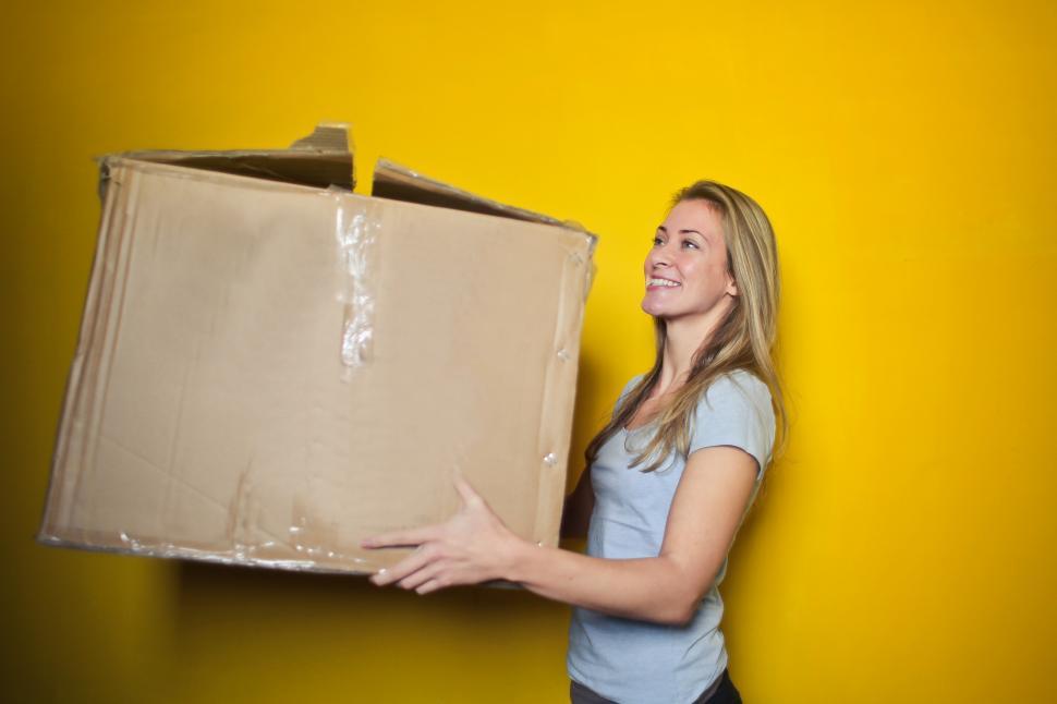Free Image of Young Woman Holding Brown Cardboard Box 