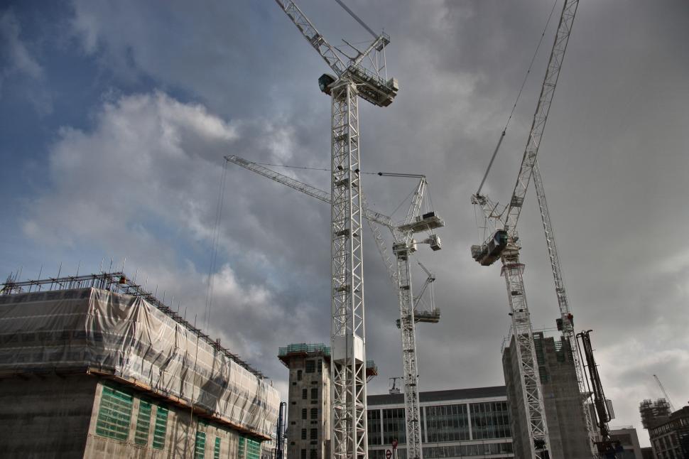 Free Image of Cranes working on a construction site, with dark clouds in the s 