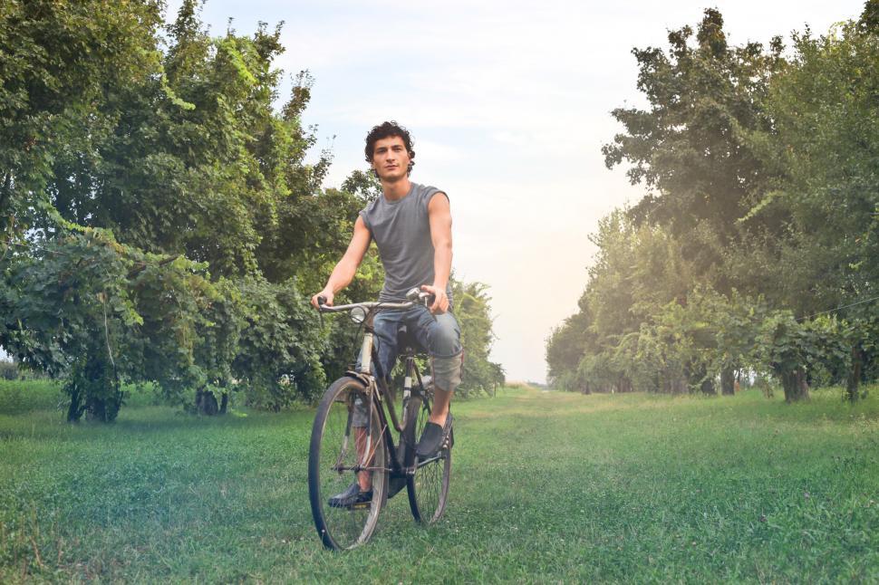 Free Image of Young Farmer Riding A Bicycle In The Meadow 