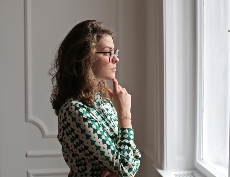 Free Image of Young woman in spectacles keeping hand on chin and looking away 