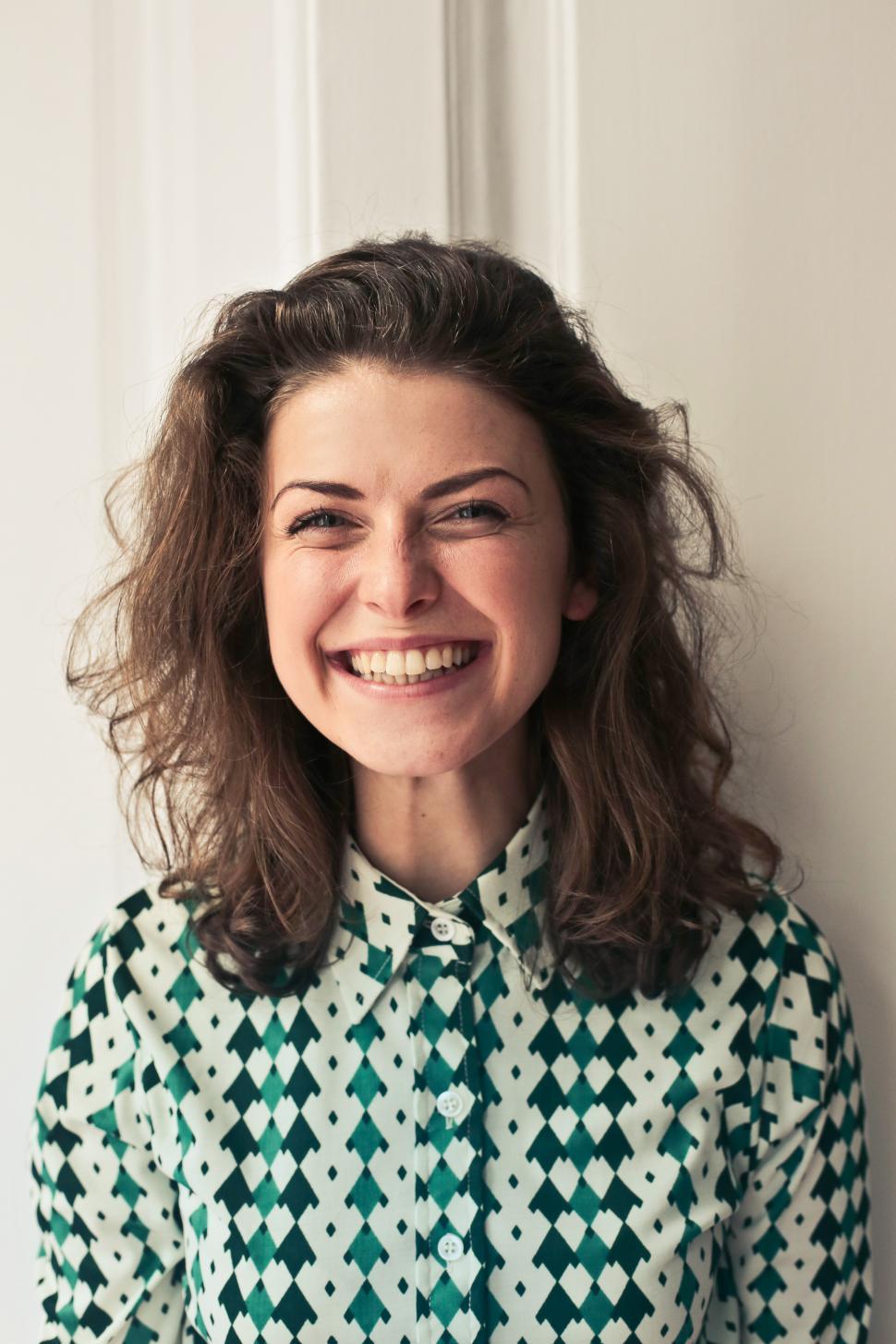 Free Image of Young woman in printed collared shirt seen smiling as looking at 