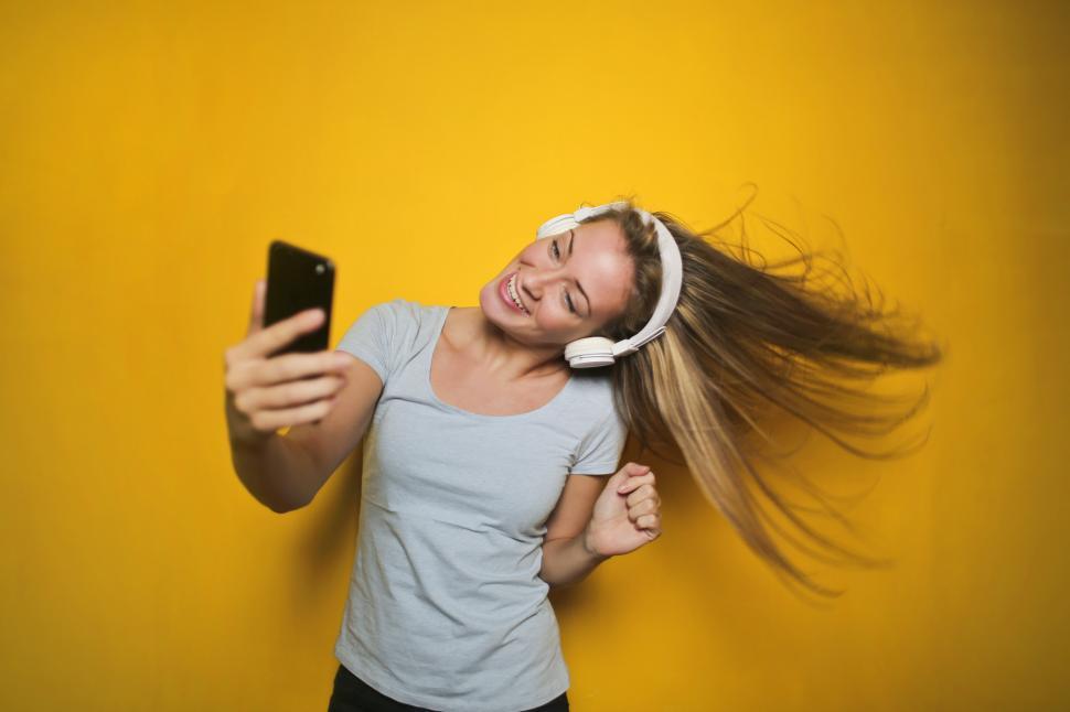 Free Image of Excited woman dancing and listening music with wireless headphon 