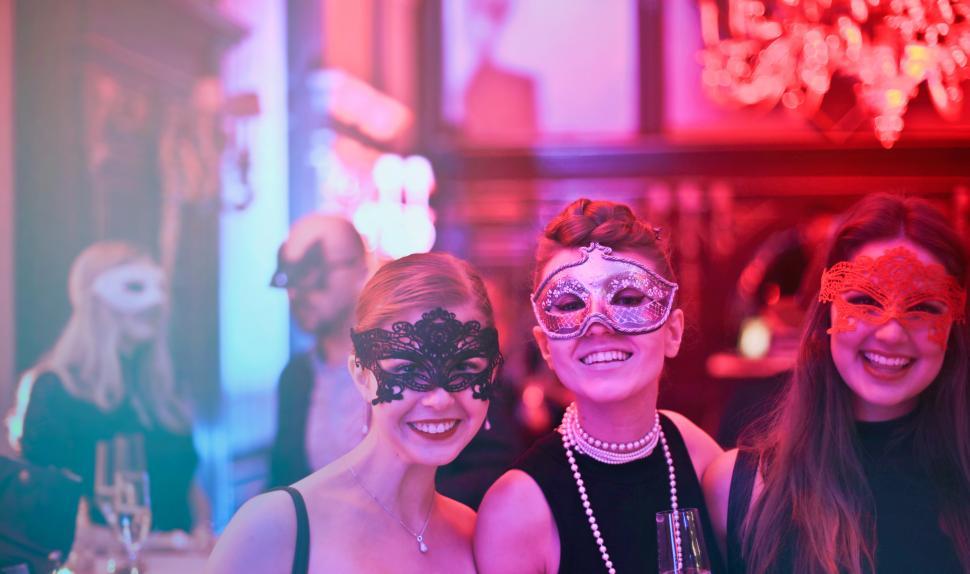 Free Image of Three Young Women In Masks Holding Wine Glasses In Nightclub 
