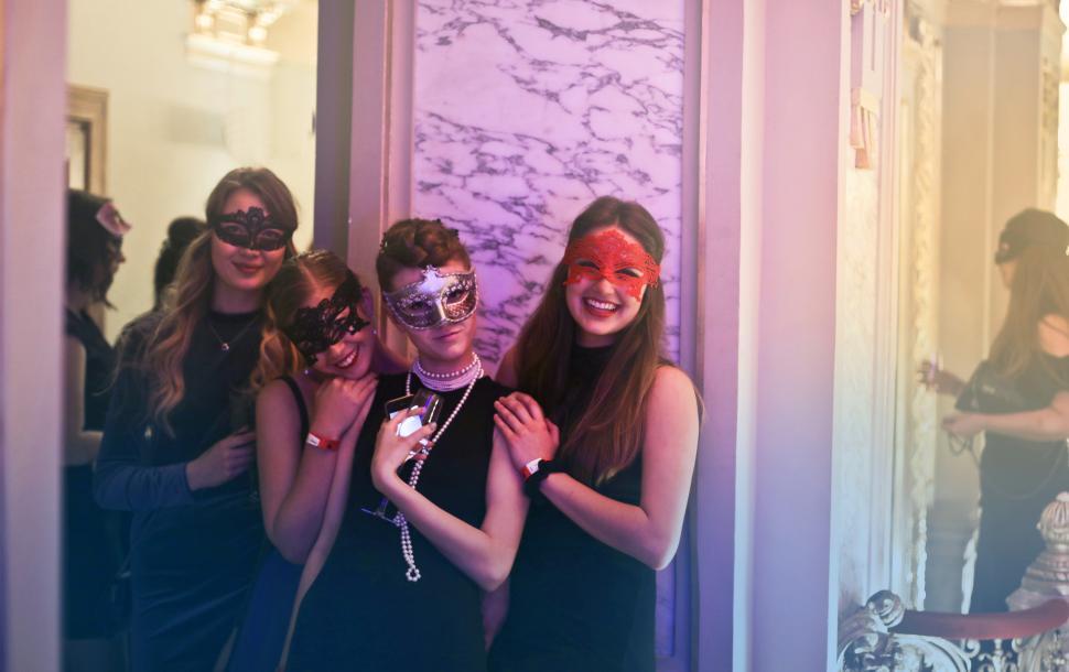 Free Image of Four Women In Masks Holding Wine Glasses In Nightclub 
