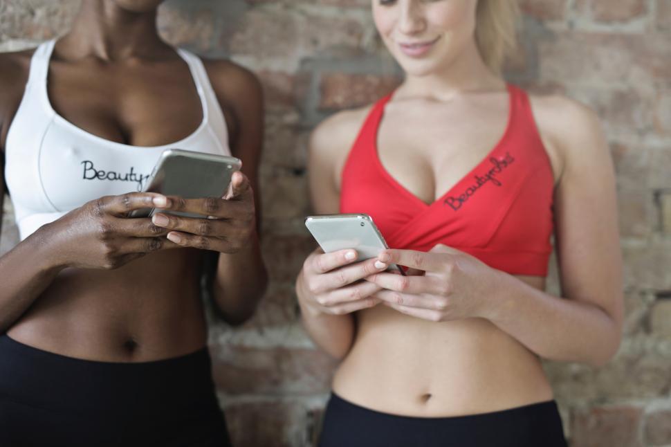 Free Image of Two young women in sportswear looking at their mobiles 