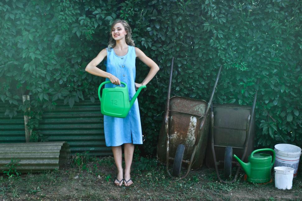 Free Image of A beautiful young woman holding a plant watering can in the gard 