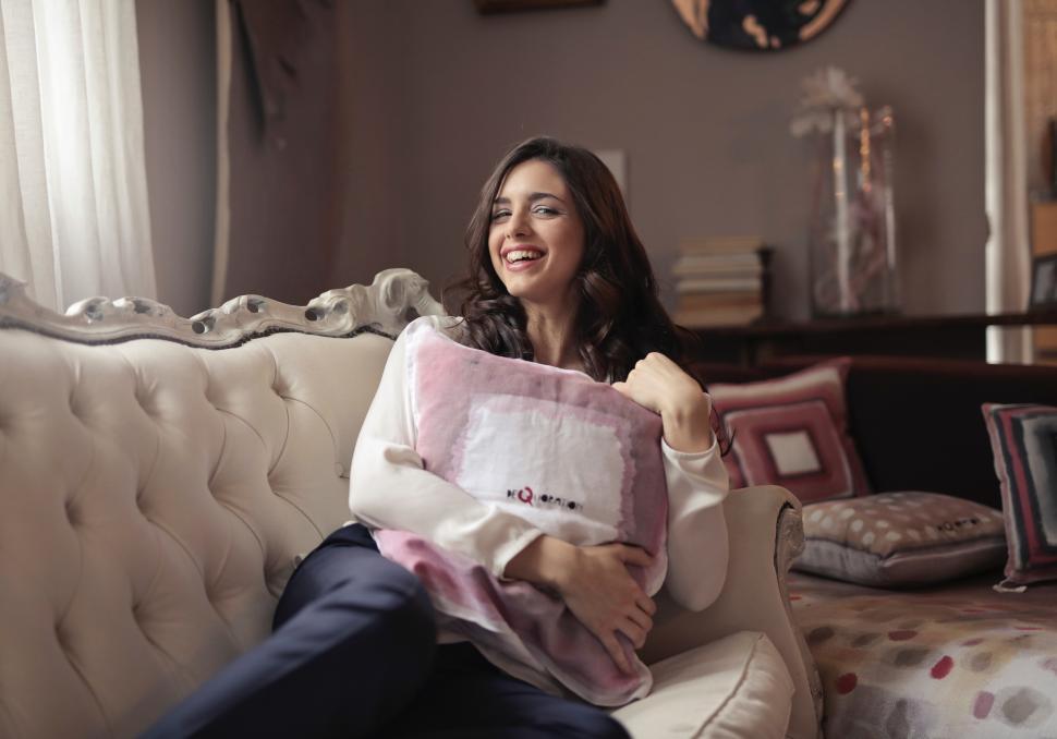 Free Image of A beautiful young woman with a smiling face embracing the cushion 