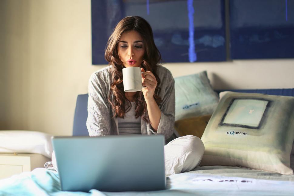 Free Image of A beautiful young woman drinking hot coffee while working on her 