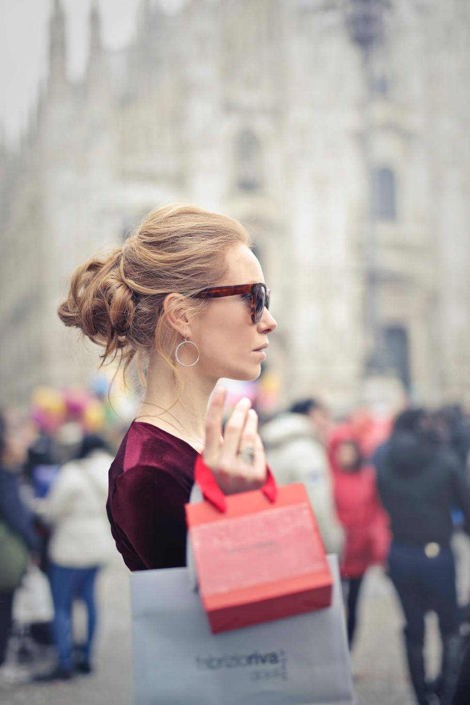Free Image of A young blond woman with elegant hair bun holding shopping bags 
