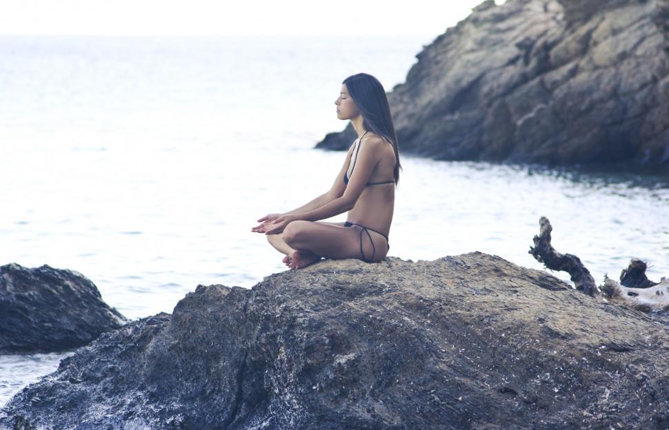 Free Image of A young brunette woman doing yoga on the beach 