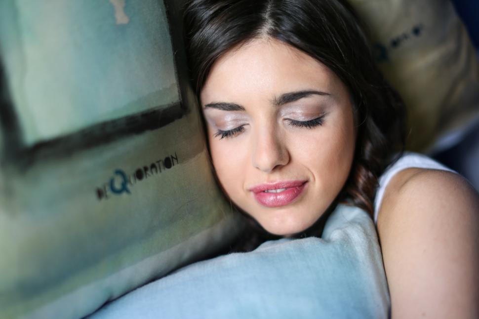 Free Image of A young brunette woman sleeping while emracing a pillow 