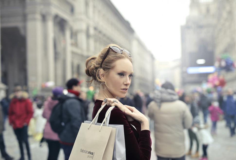 Free Image of A young blond woman holding shopping bags in her hands on her sh 