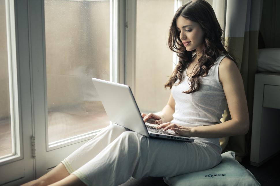 Free Image of A young woman working on her laptop by the window 