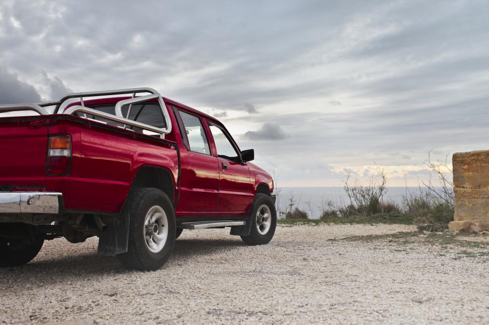 Free Image of A red pick-up truck parked by the sea 
