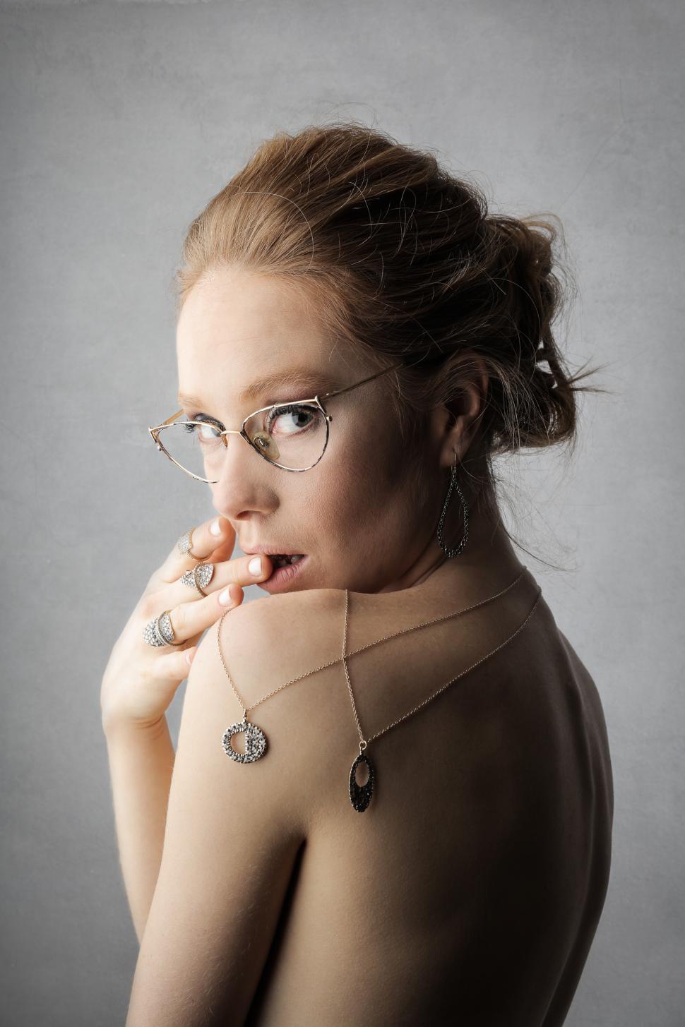Free Image of A young blonde woman wearing jewelry looks over her shoulder 