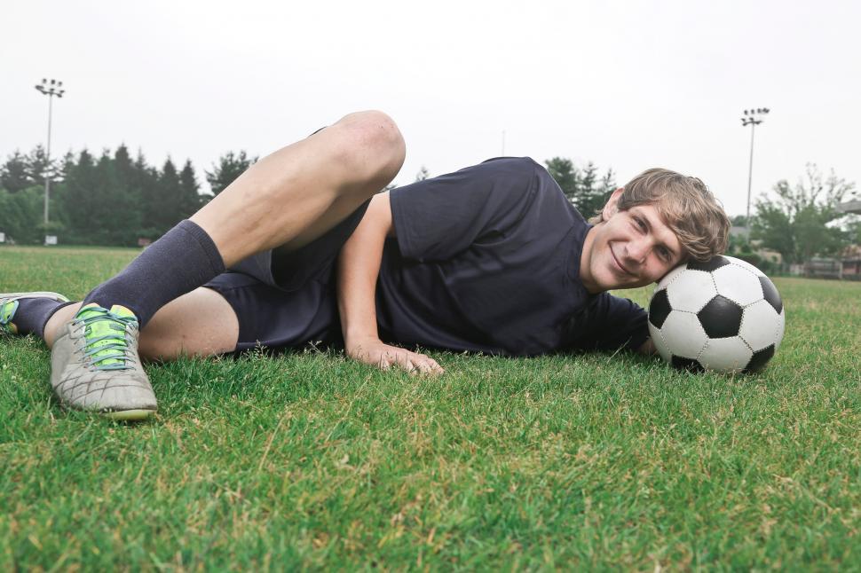 Free Image of A soccer player posing with football on the grass 