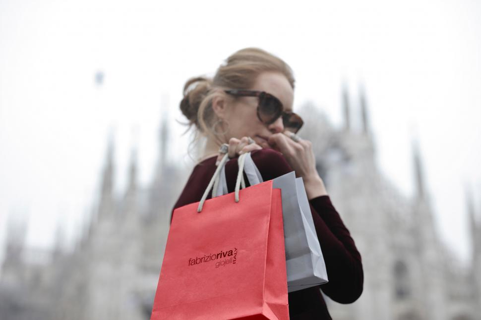 Free Image of A young blonde woman holding shopping bags in her hand looks ove 