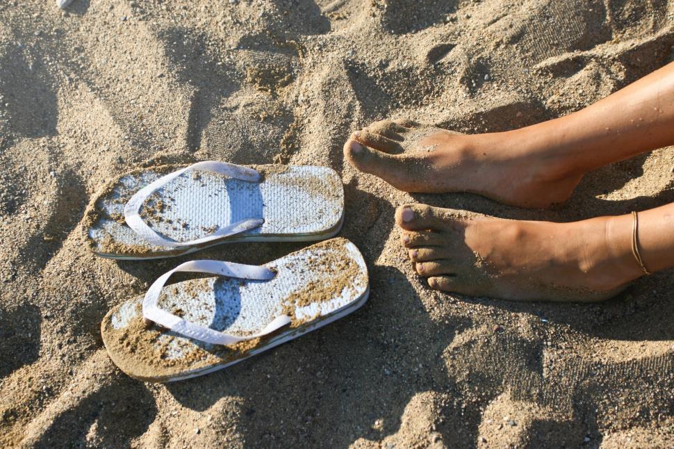 Free Image of Relaxed feet on the sand with slippers 