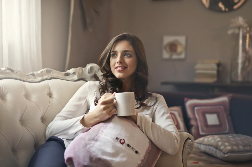 Free Image of A young woman sitting on the couch holding a coffee mug in her h 