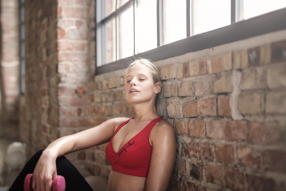 Free Image of A young blonde woman relaxing in the gym with a bumbbell in her 