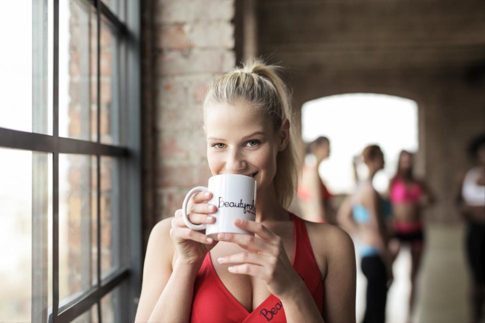Download Free Stock Photo of A young blonde woman wearing red sports bra holding coffee mug i 
