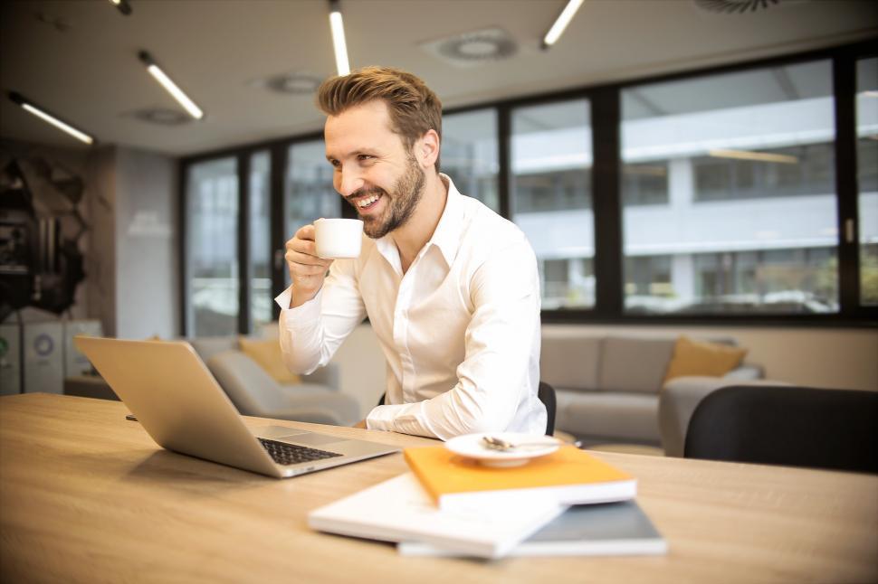 Free Image of A young bearded caucasian man looking at his laptop screen while 